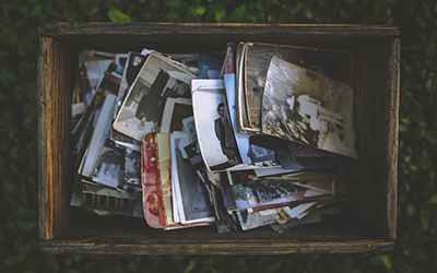 Aerial shot of a wooden box on a lawn and filled with 5x7 and 4x6 photographs.